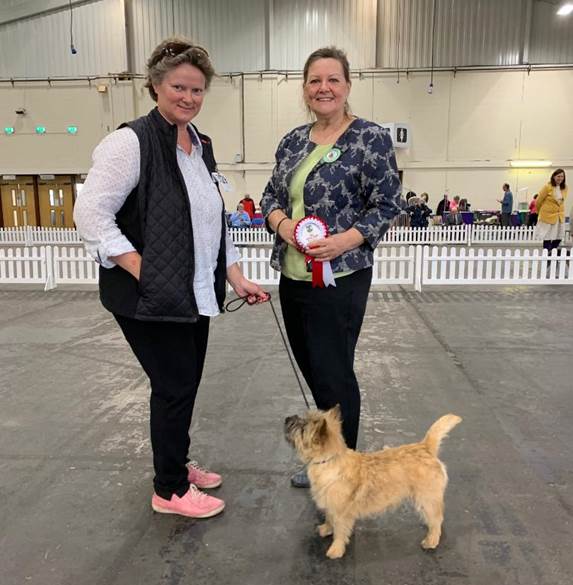 Two women standing next to a dog

Description automatically generated